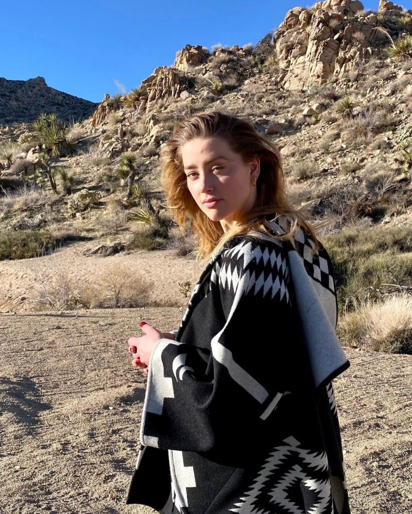 Amber Heard posing in a desert land wearing black and white kaftaan