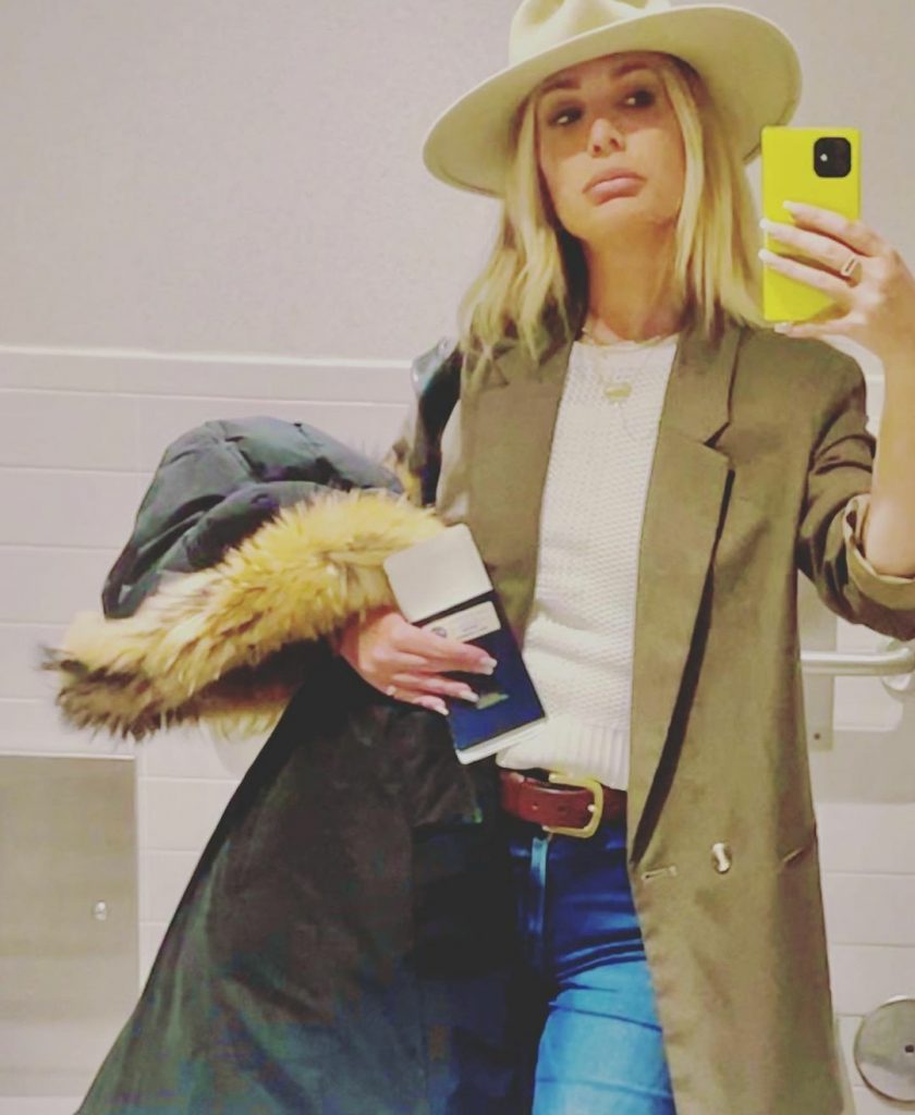 Kate Chastain wearing a brown coat and yellow phone