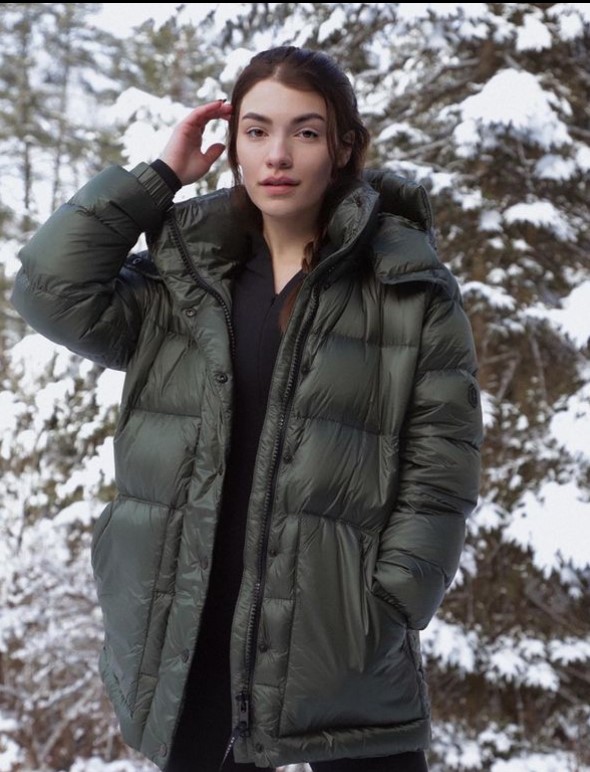 Livia wearing a black coat posing in a area covered with snow.