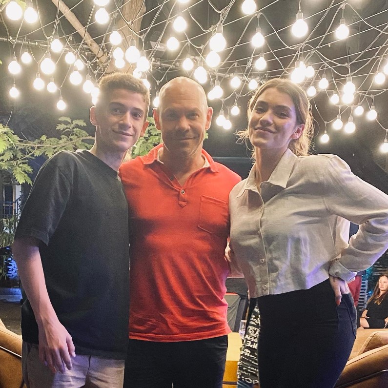 Livia with her father and brother. she is wearing a white colored shirt.