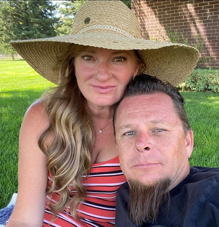 Charity with her husband Dave Kindig wearing a brown hat and red striped top.