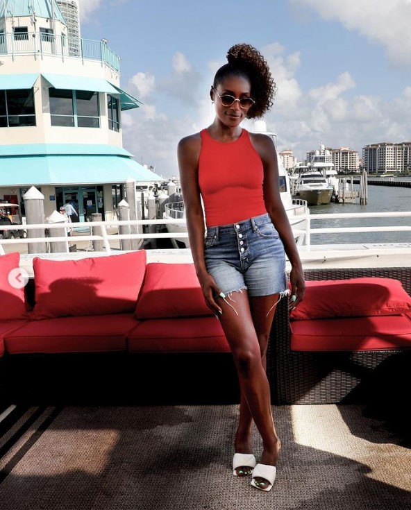 Issa Rae at Miami wearing orange top and blue shorts
