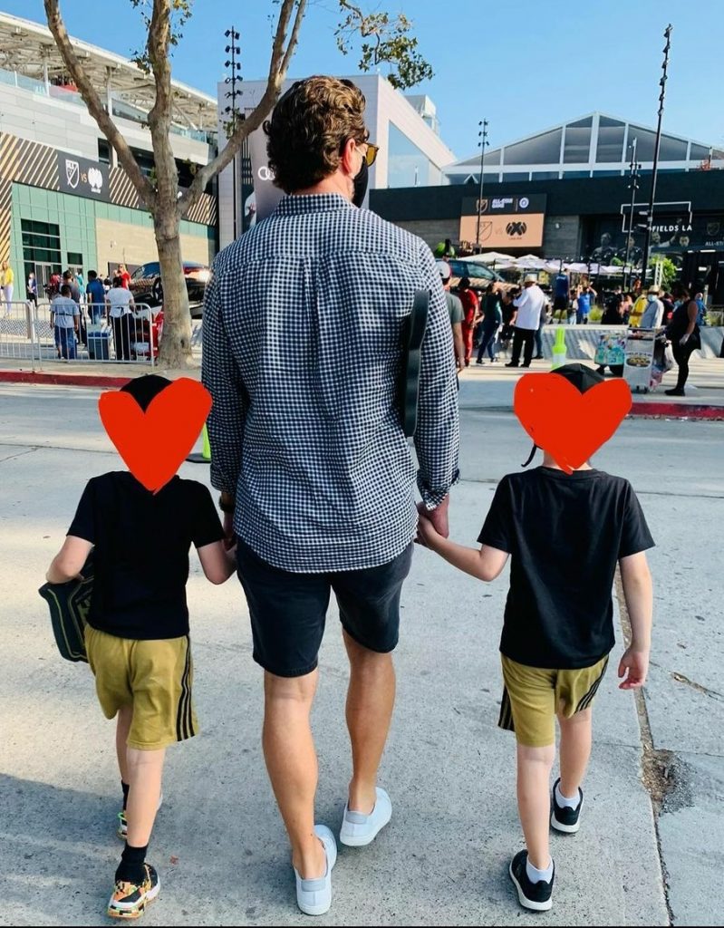 Hugo Wilson Dallas with his father and sibling wearing a black t shirt.