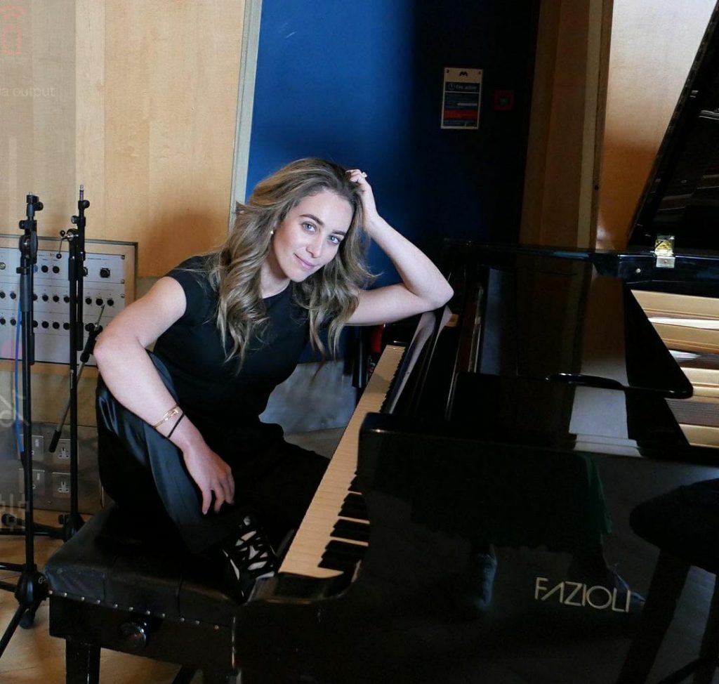 Chloe Stroll wearing black clothes posing with her piano.