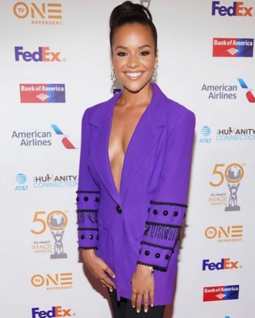 Alyssa at NAACP Image Awards wearing a purple colored coat and black bottoms.