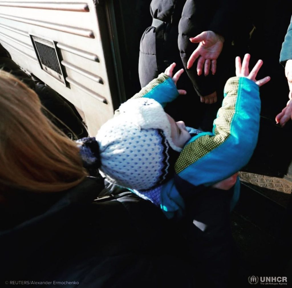 A kid wearing white cap and blue jacket