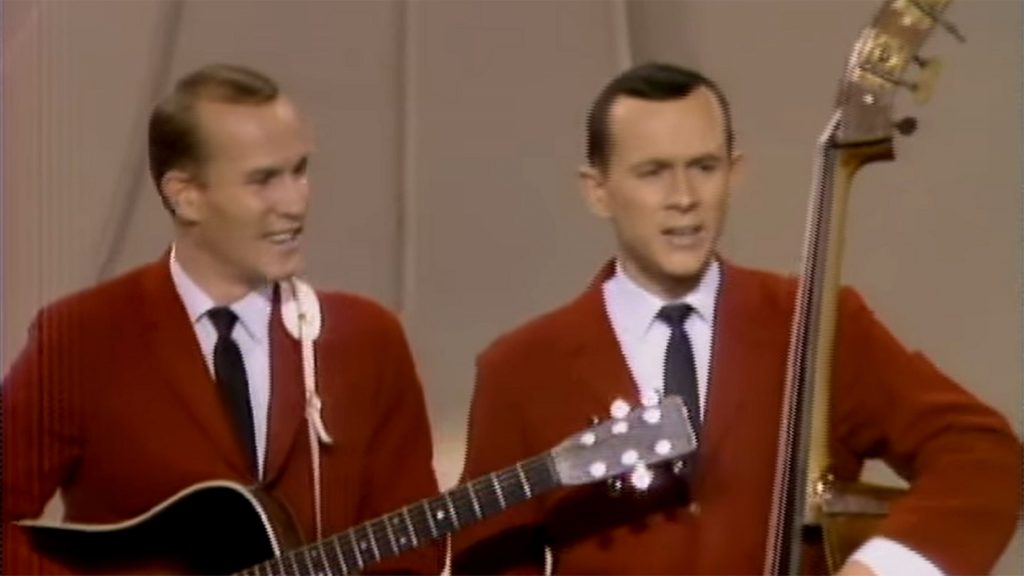 Smothers brother playing guitars wearing red suits