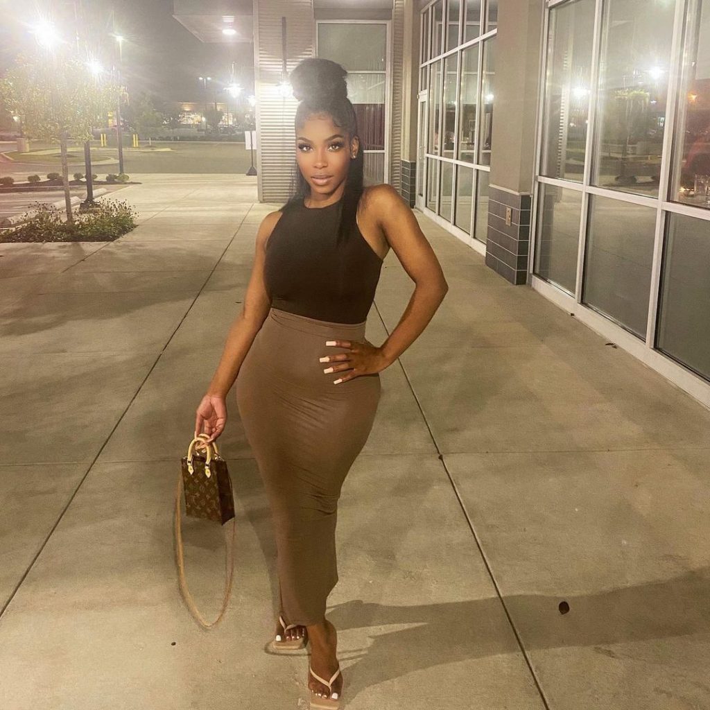 Arionne wearing a black top and brown body fit skirt from her brand Aris 