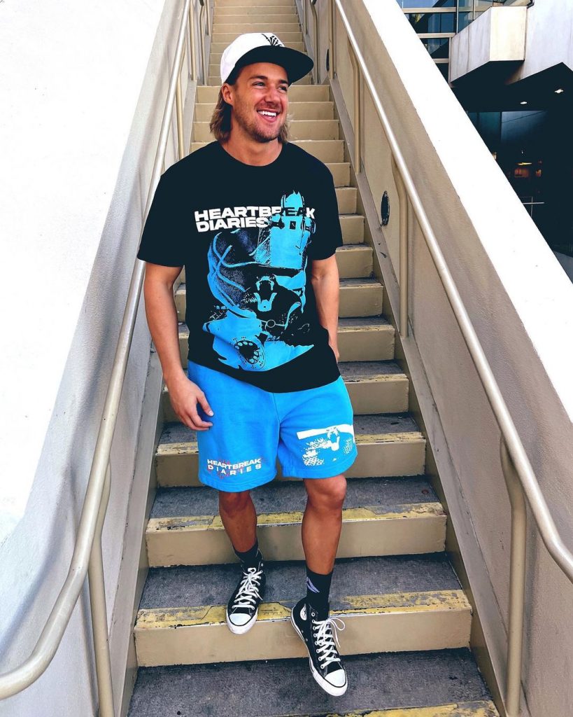 CLowdus wearing blue shorts and black printed tee