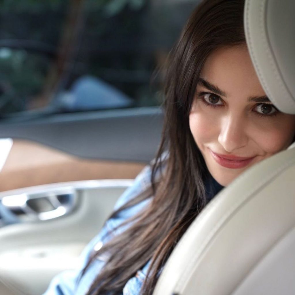 Ozge Gurel posing sitting in a car