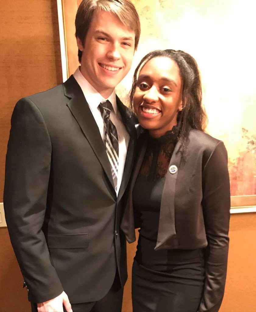 Dakota wearing a black suit posing with his childhood friend.