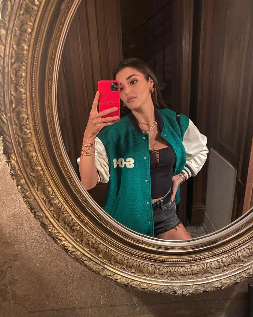 Hande taking a mirror selfie weaing a green colored jacket.