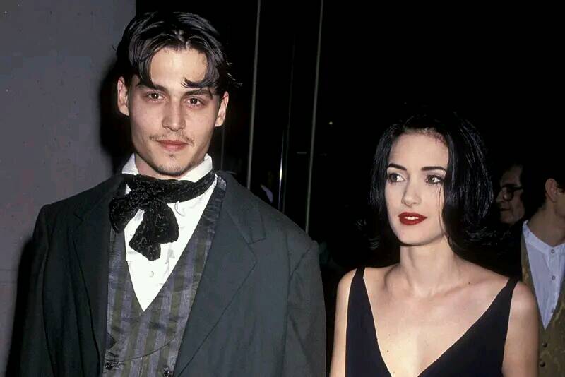 Winona Ryder and Johnny Depp from the time they were engaged. Both are wearing black and holding each other's hands.