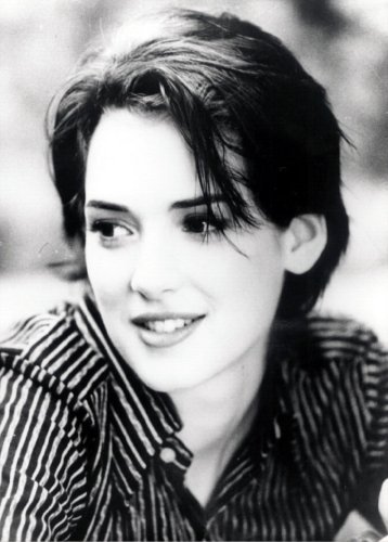 Winona Ryder wearing a black striped shirt looking on the other side of the camera.