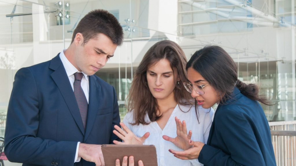 A man showing his diary to two women in office.