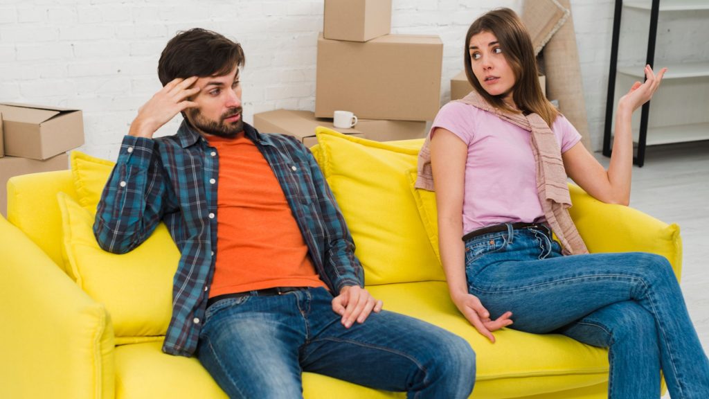 A girl and boy sitting on a sofa.