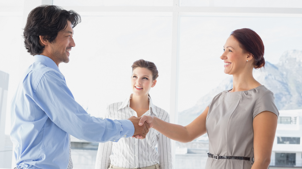 A girl wearing a grey dress is shaking hands with a boy wearing blue shirt.