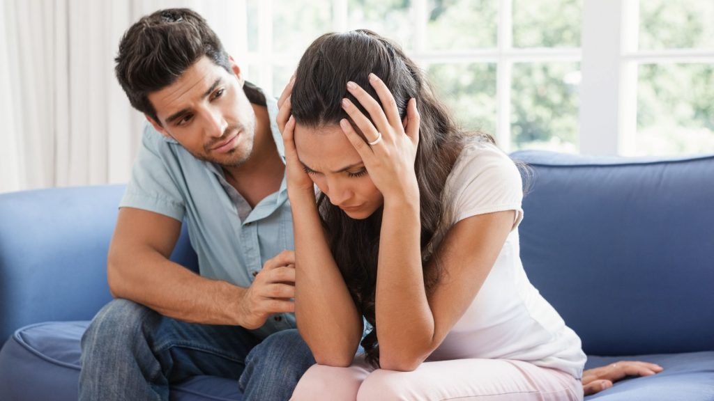 A man sitting with a female consoling her.