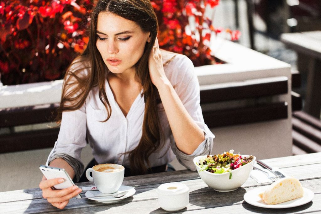 A girl eating food and having coffee in a restaurant.