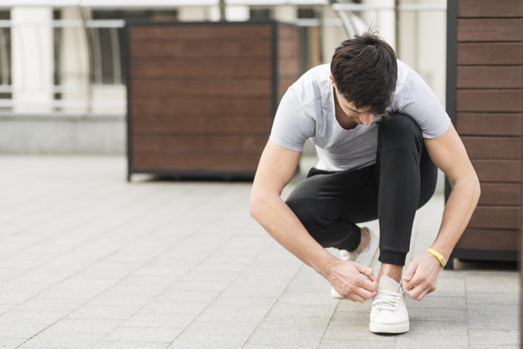 A man wearing his white shoes.