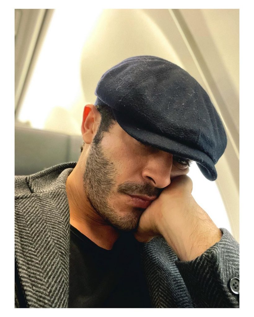 Burak Deniz wearing a hat and taking selfie in his flight.
