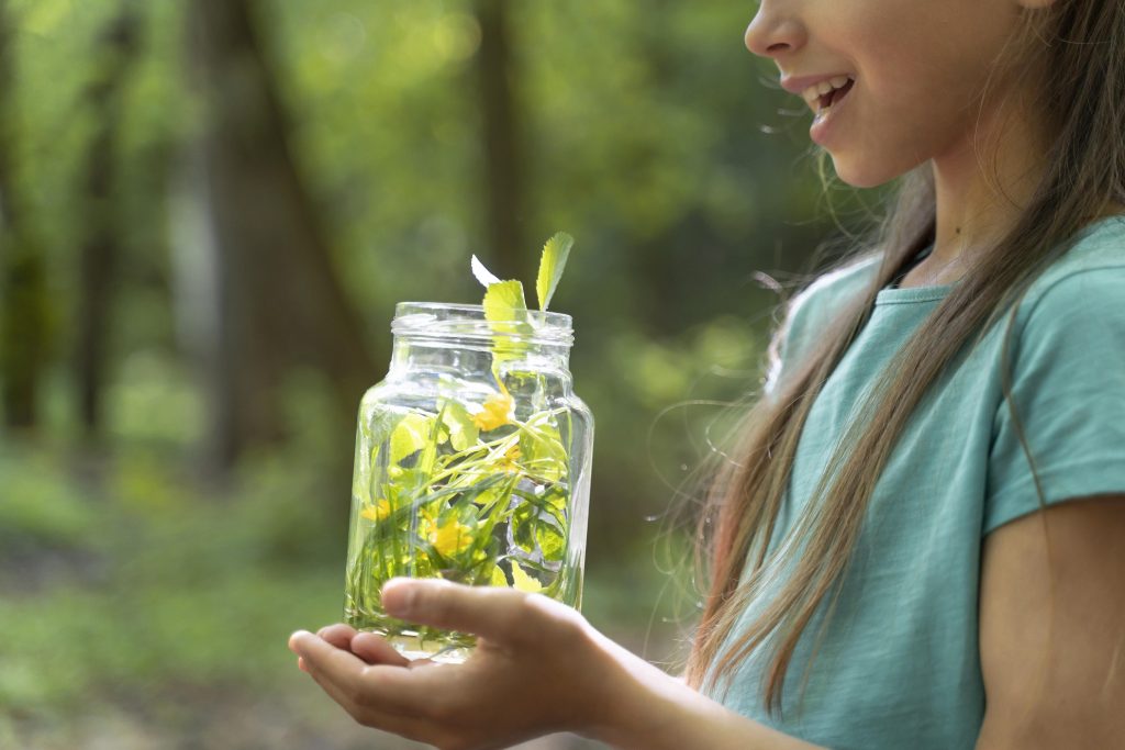 A girl holding a bottle and a plant grown in it.