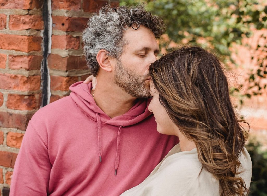 A man kissing on his partner's forehead showing affection.