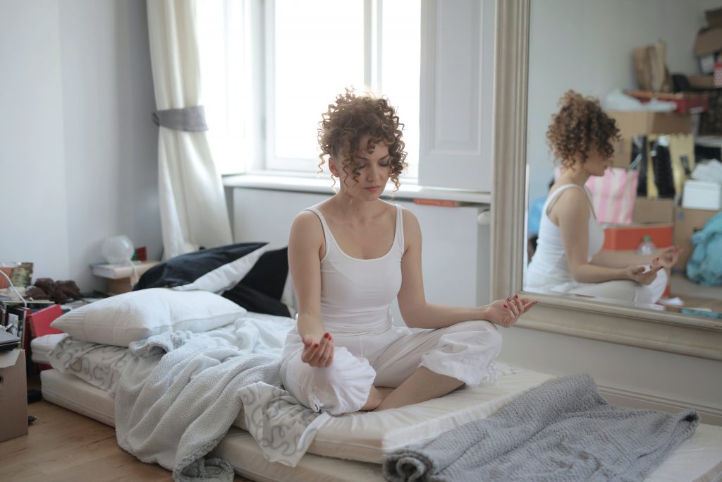 A girl sitting doing breathing exercises in her room.