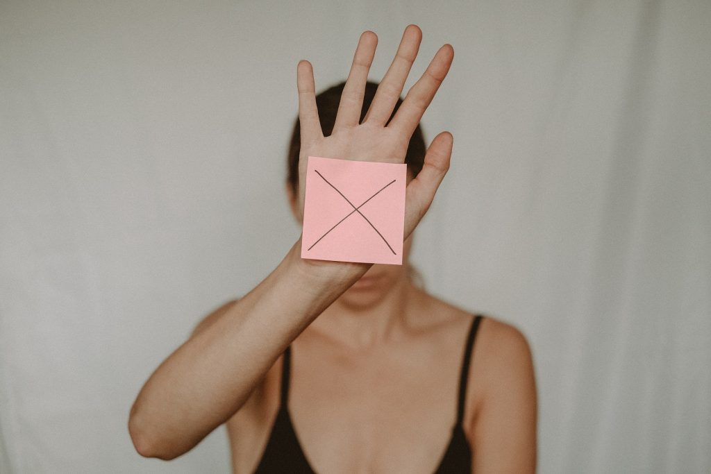 A girl holding a sticker with cross on her hand.