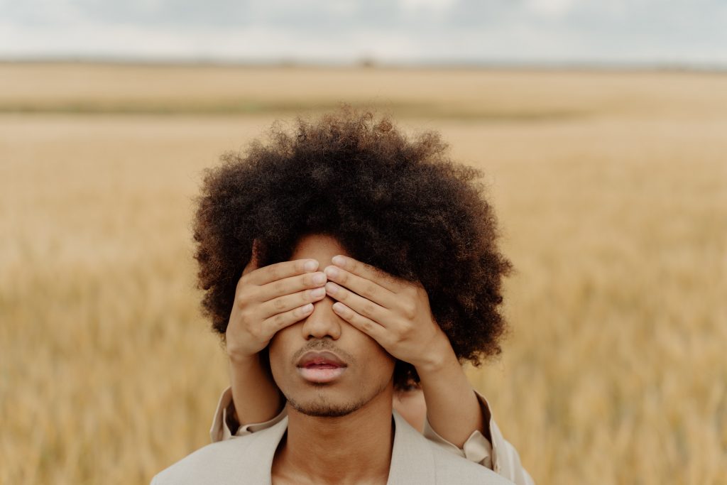 A man eyes has been covered with women's hands.