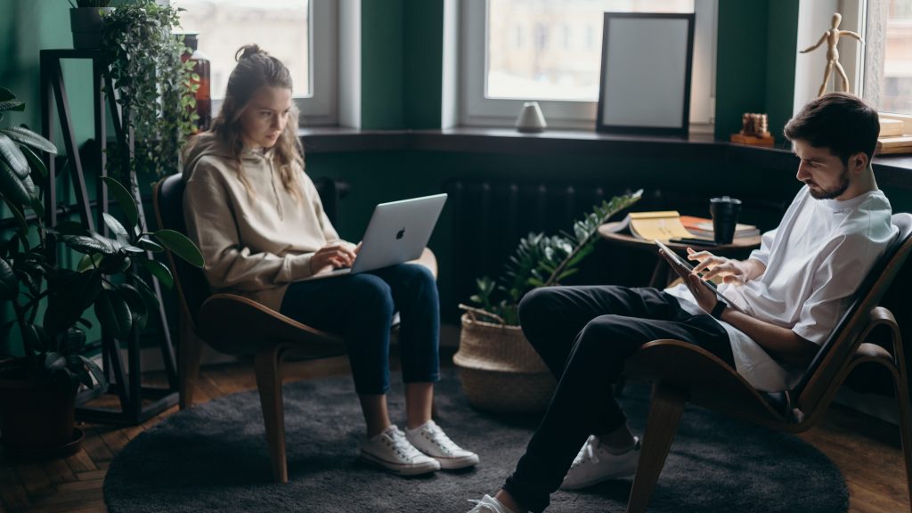 A couple working on their own gadgets focusing on their work.