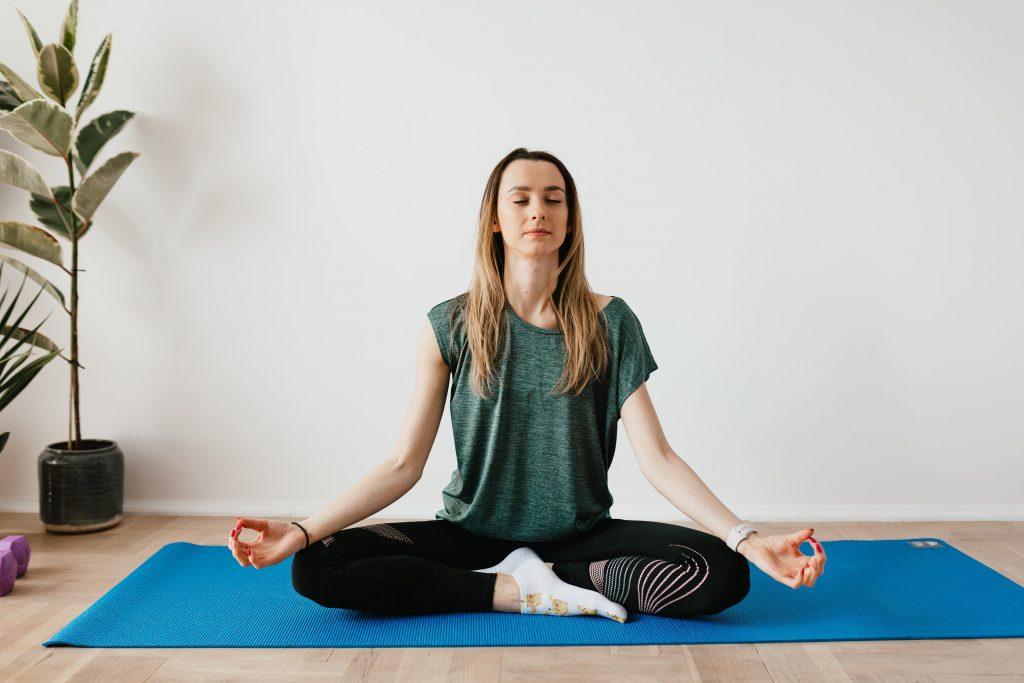 A female meditating at her home.