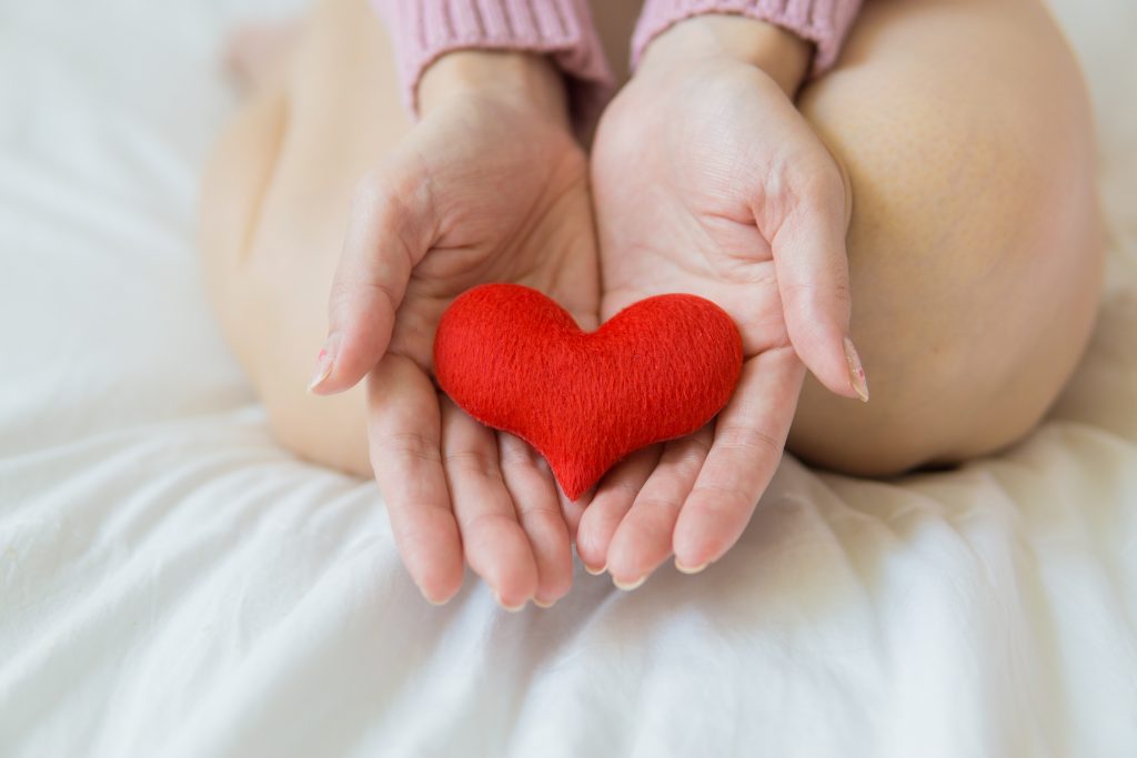 A woman holding a little heart in her hand.