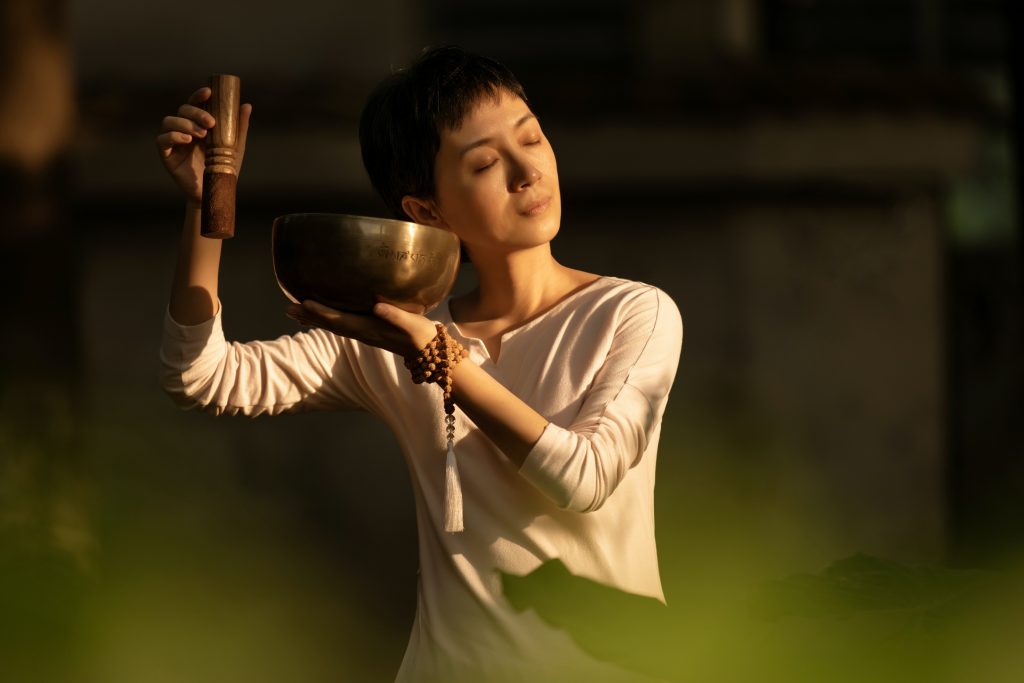 A female practicing buddhist sound bowl for meditation.