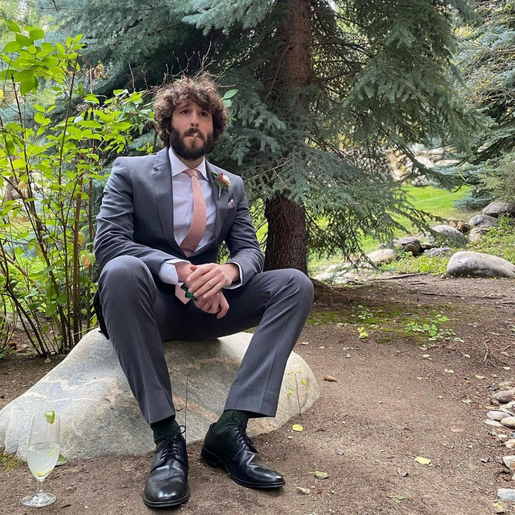 Lil wearing a suit and sitting on the rock.