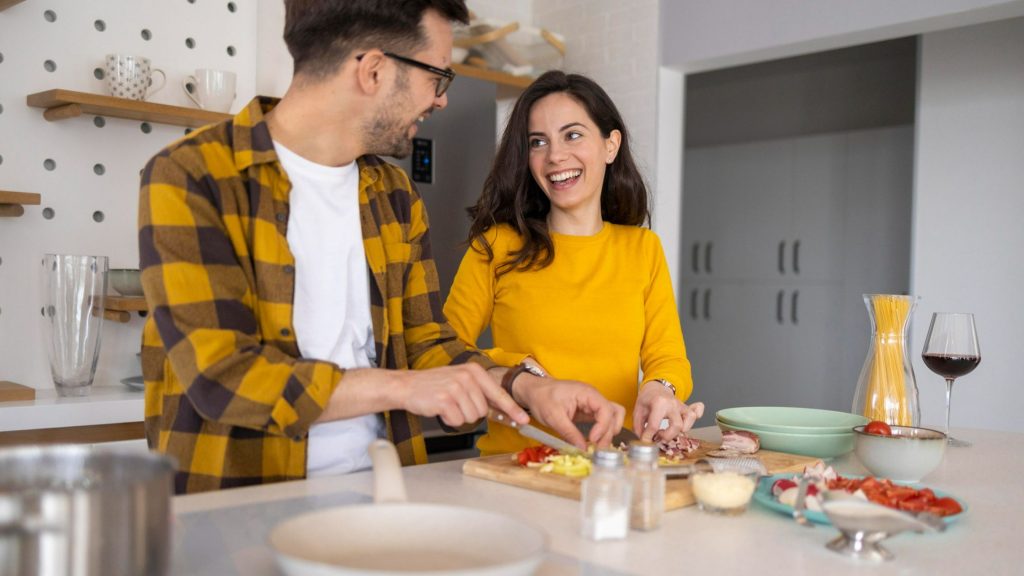 A couple wearing same color clothes preparing dinner together.