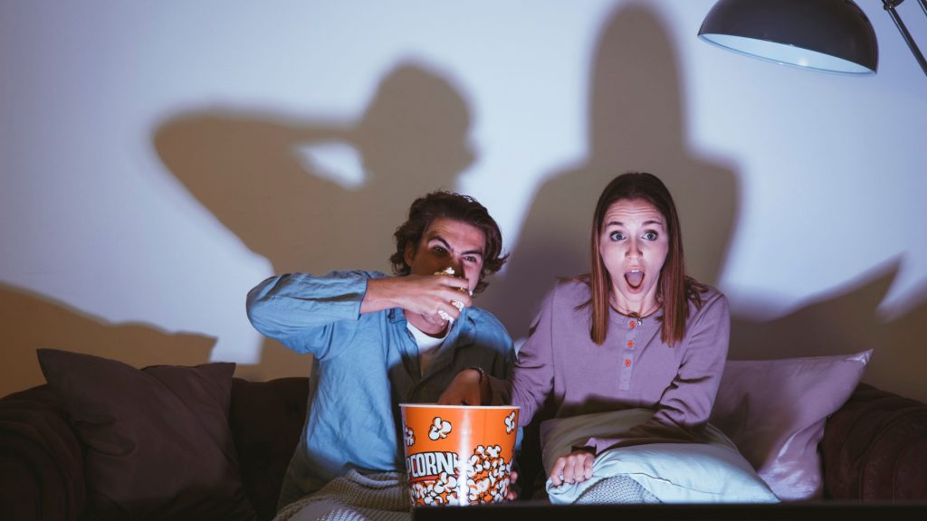 couple watching movie and eating popcorn together to spice up romance in relationship.