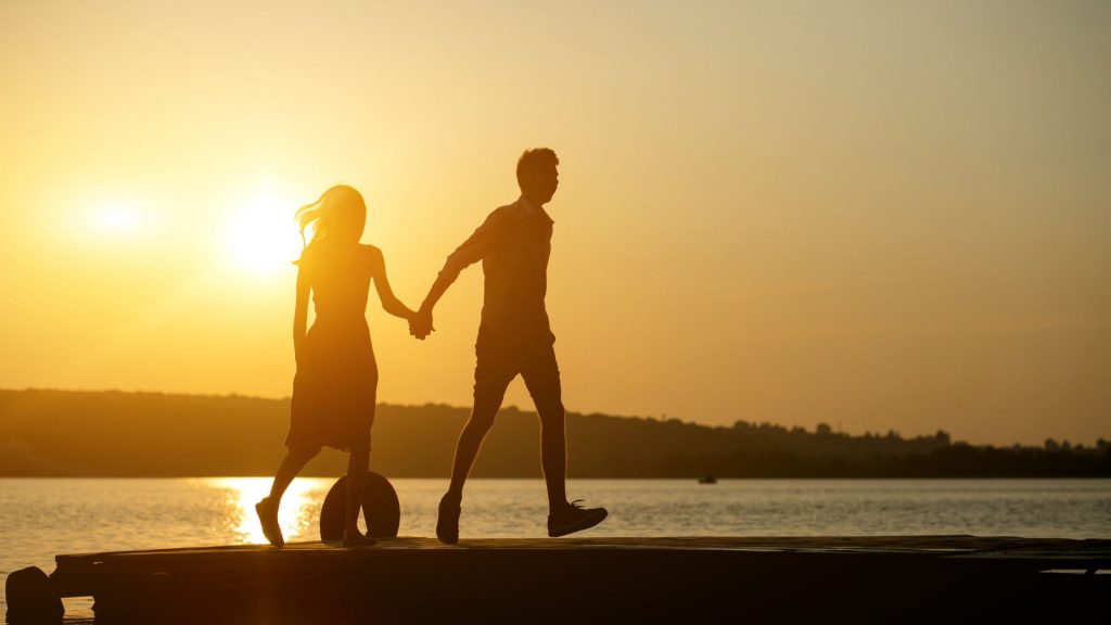 romantic couple enjoying a walk and sunset on beach.