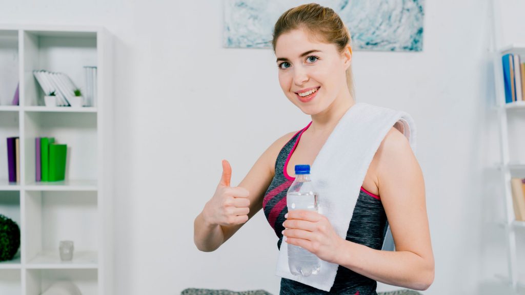 A girl holding a bottle of water after workout.