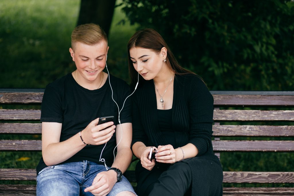 A girl and a boy listening using same earphones.