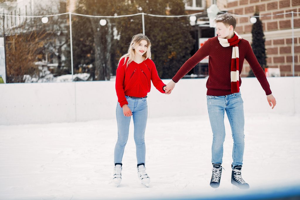 Couple in a ice arena. Elegant girl in a red sweater.