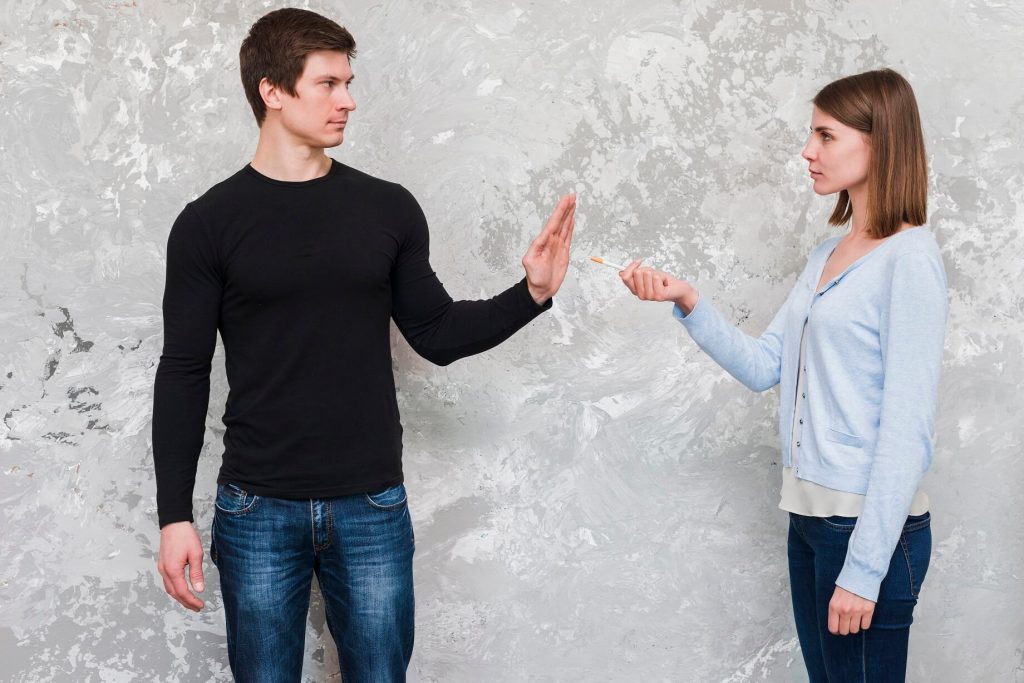 young-man-saying-no-woman-offering-cigarette-standing-near-old-wall